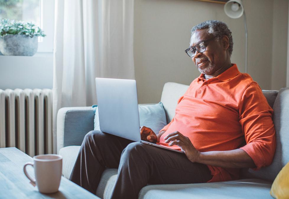 Senior man sitting on couch looking at laptop