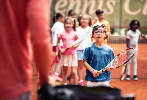 Kid with glasses with a tennis racket