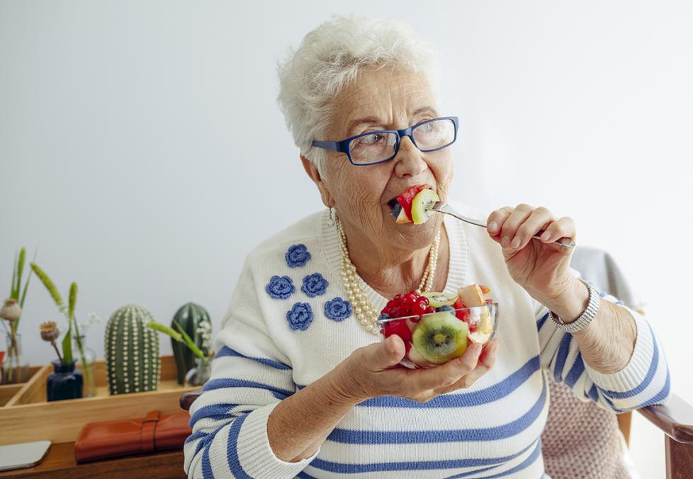 Old woman eating a fruit bowl