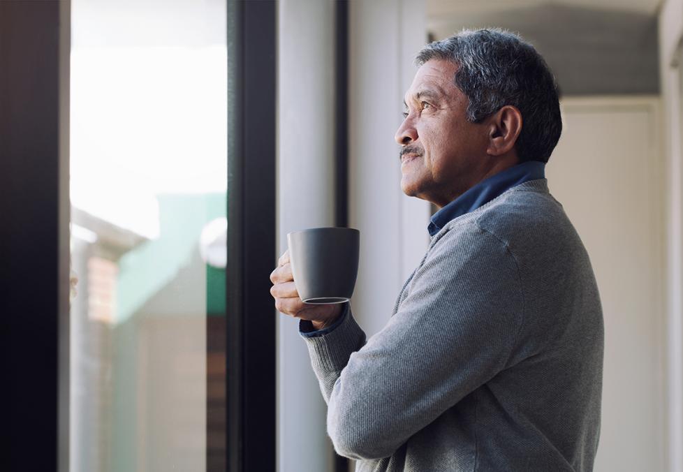 Older man drinking coffee and looking out the window