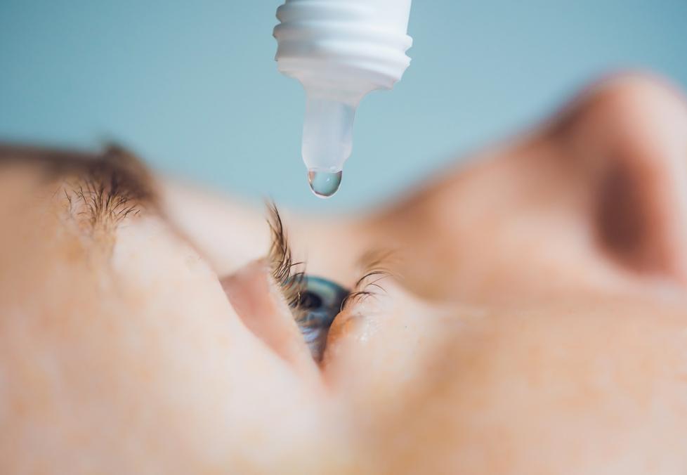 A closeup of someone using eye drops