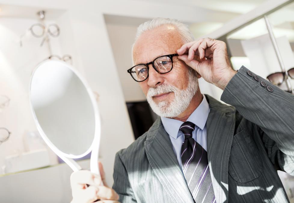 Man in suit trying on eyeglasses.