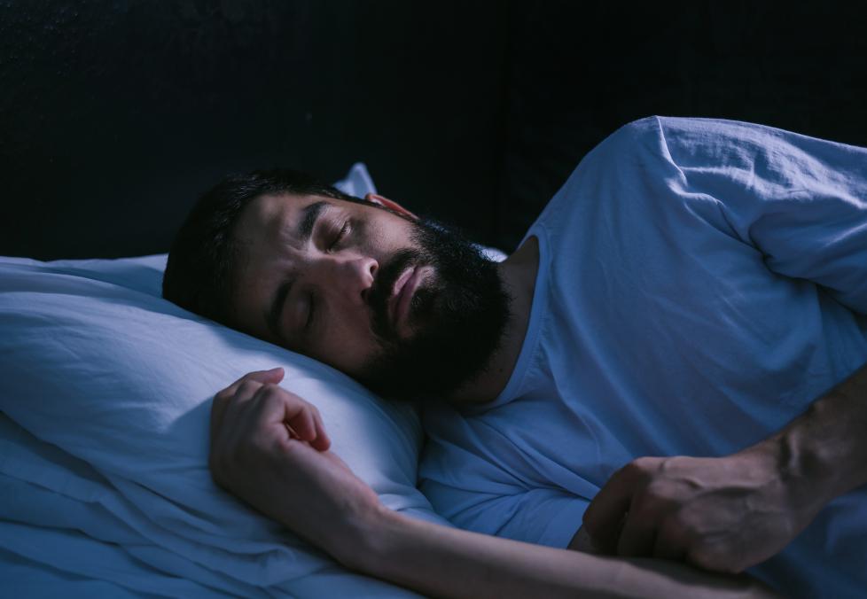 Your eye health depends on getting enough sleep. Man with beard sleeping.