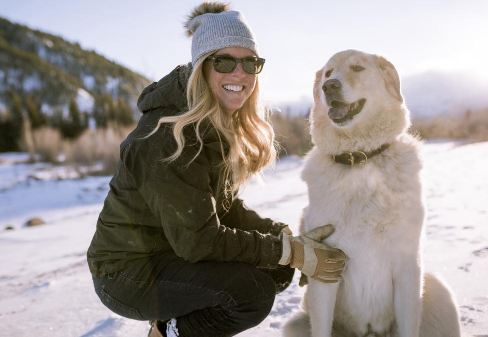Woman in winter wearing sunglasses with her dog.