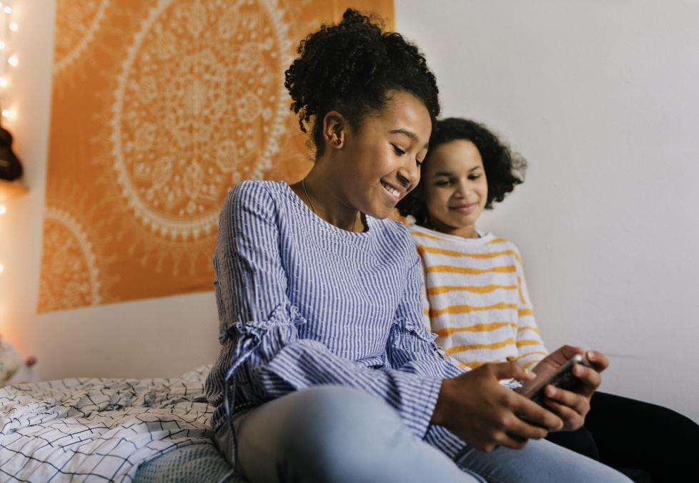 Two girl kids looking at a phone and smiling 