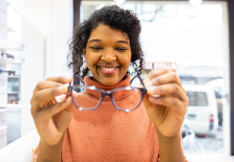A smiling woman trying on new glasses frames