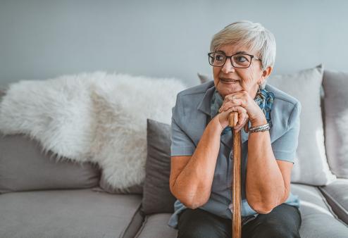 Old woman with a cane sitting on the couch