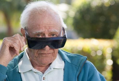 An old man peeking over his bulky sunglasses