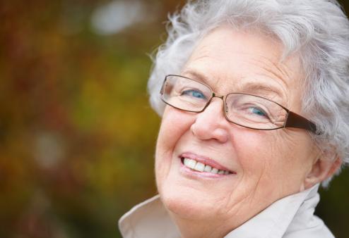 An old woman with glasses smiling into the camera
