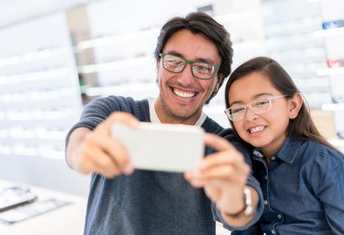 Dad and daughter taking selfie buying glasses.