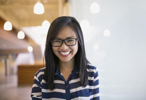 A young woman wearing glasses and smiling