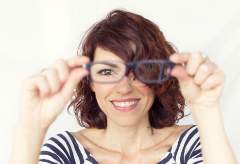 Woman holding glasses in front of her face.
