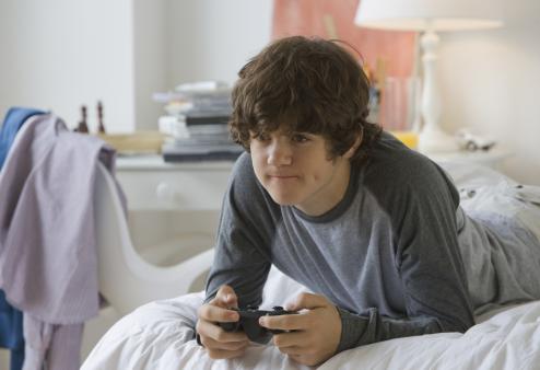 Boy in bedroom playing video games.