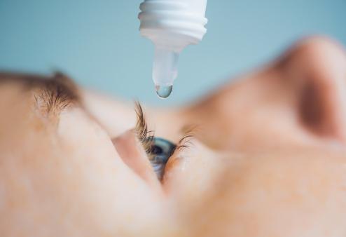 A closeup of someone using eye drops