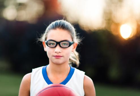 Girl wearing sports goggles holding basketball
