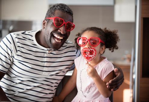 A man and his daughter wearing heart-shaped glasses
