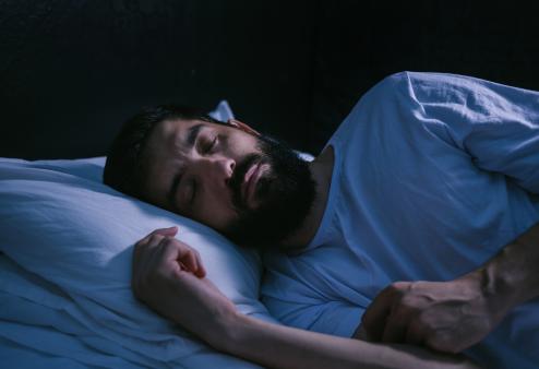 Your eye health depends on getting enough sleep. Man with beard sleeping.