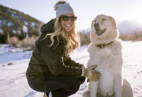 Woman in winter wearing sunglasses with her dog.