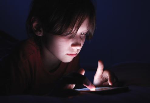 Young girl using her smartphone in the dark.