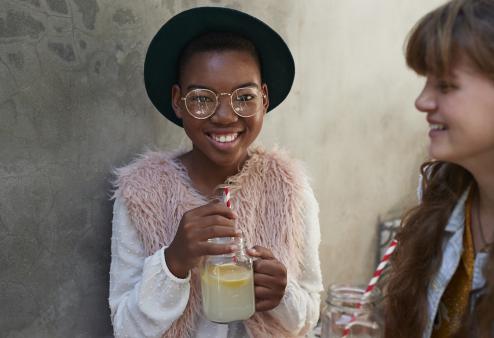 Preteen girl wearing glasses holding lemonade.