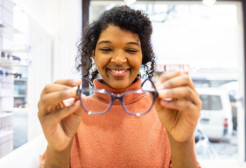 African American woman smiling and trying on new glasses
