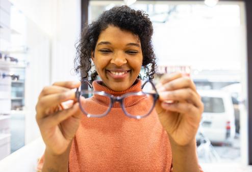 A smiling woman trying on new glasses frames