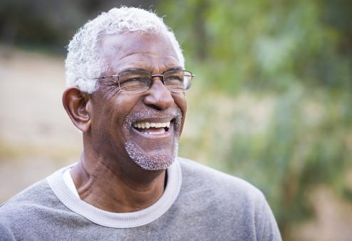 An older man wearing glasses smiling