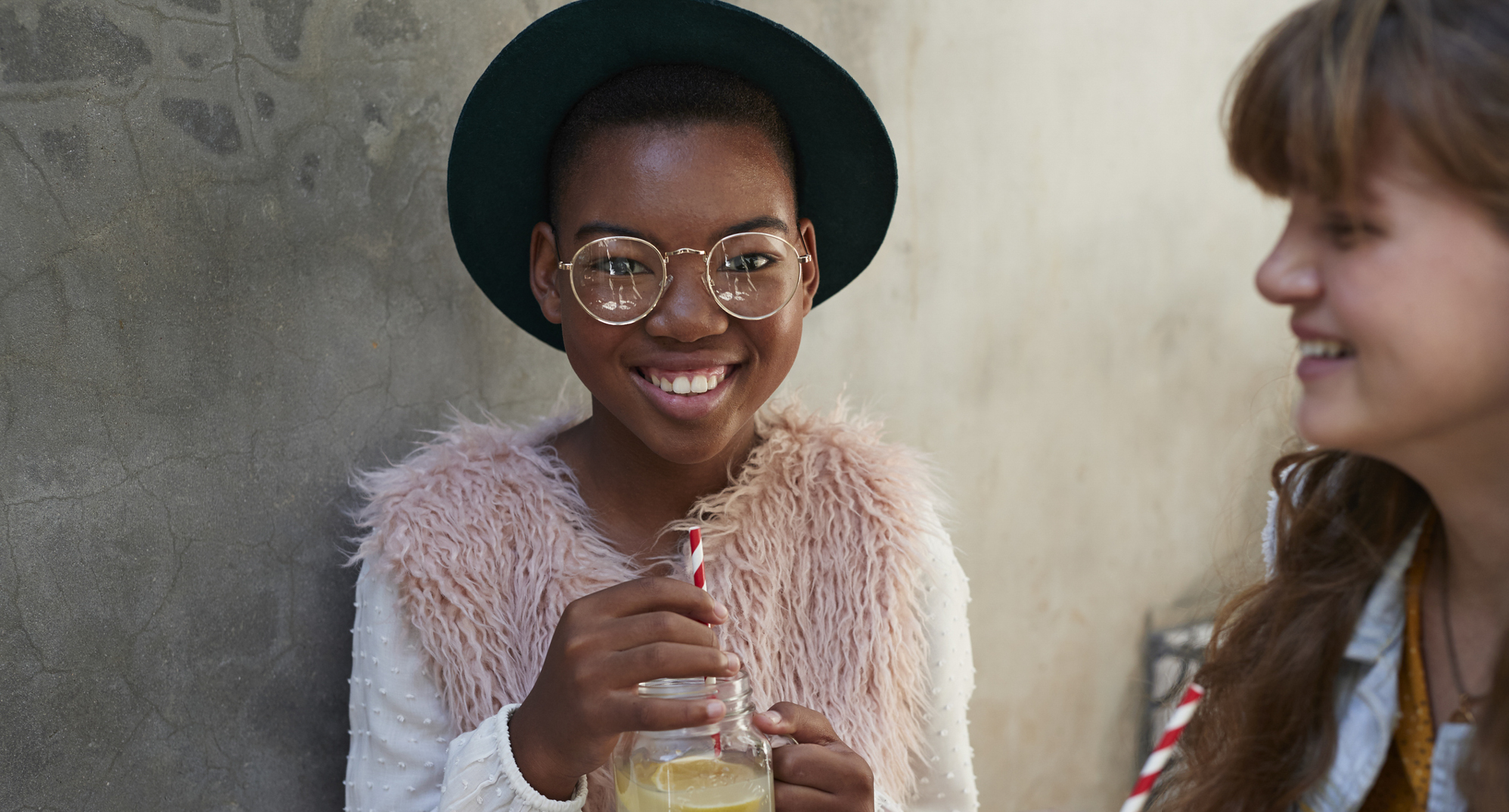 Preteen girl wearing glasses holding lemonade.