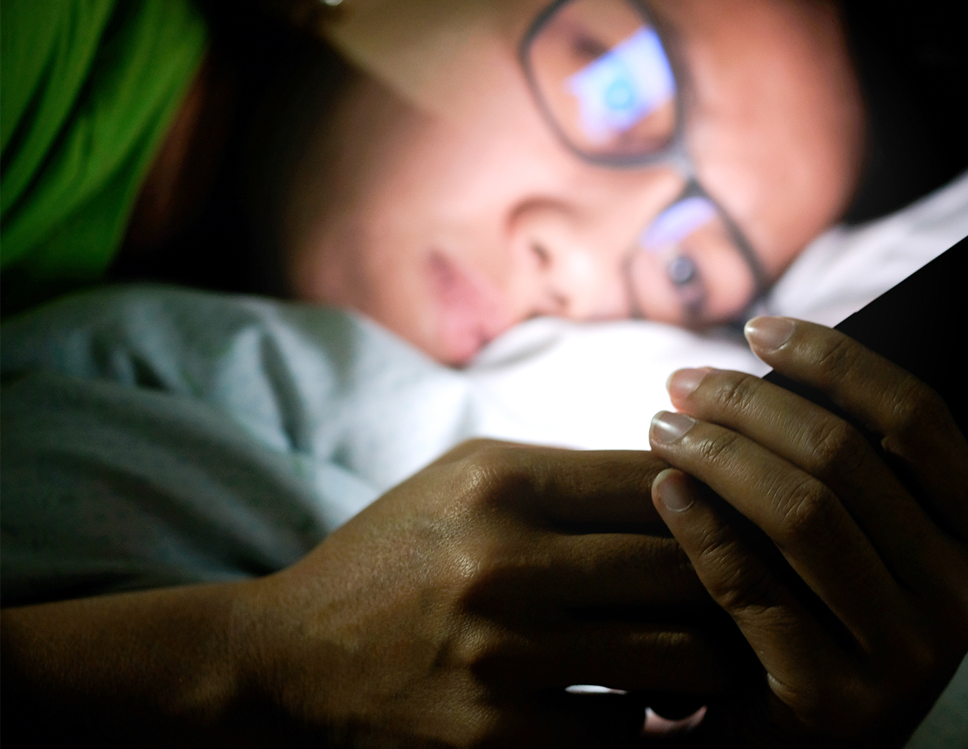 Woman looking at phone in bed at night